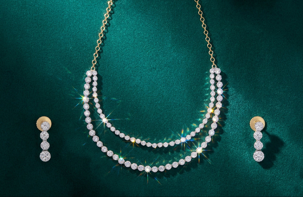 A gold-tone necklace and matching drop earrings set with sparkling clear gemstones, arranged on a deep teal-green textured background.