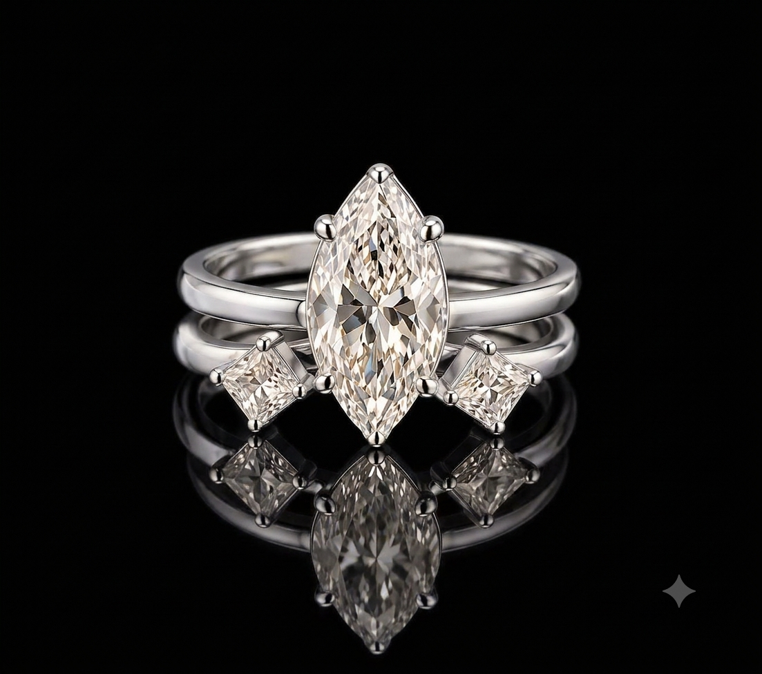 A white gold ring set featuring a marquise-cut center stone with two smaller kite-cut side stones, displayed on a reflective black surface against a black background.