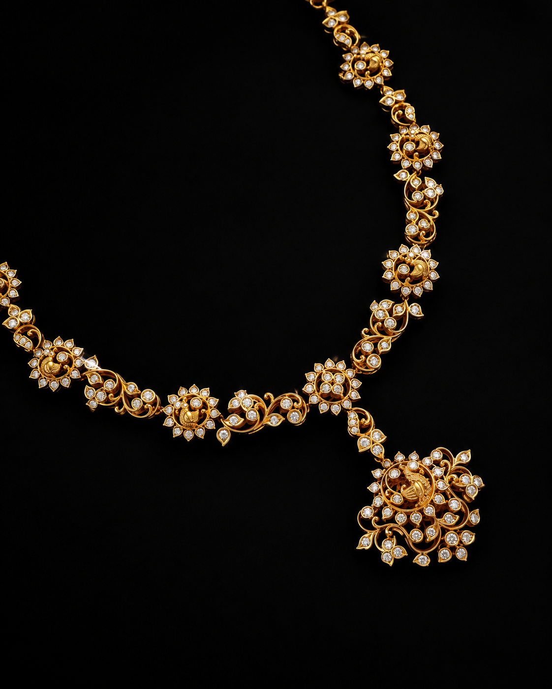 An ornate gold necklace with intricate floral motifs set with small clear stones, displayed against a solid black background.