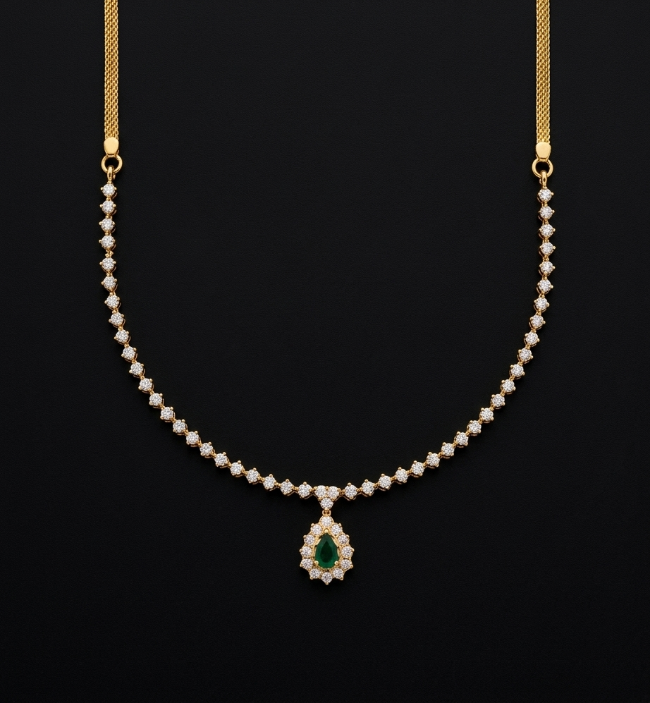A South Indian gold necklace set against a black background. The chain is composed of small repeating floral or square-like clear stone clusters leading down to a central teardrop pendant featuring a green emerald gemstone framed by halo-set clear stones.