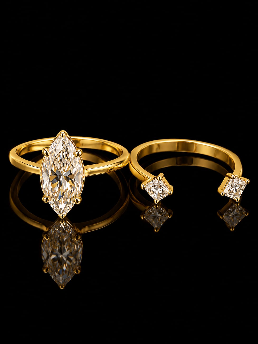 A pair of yellow gold rings displayed on a reflective black surface. One ring features a large marquise-cut diamond, and the other is an open band ring with two Kite-cut diamonds.