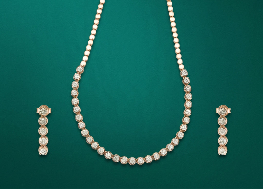 A gold necklace and matching drop earrings set with round clear gemstones, arranged symmetrically on a solid dark green background.