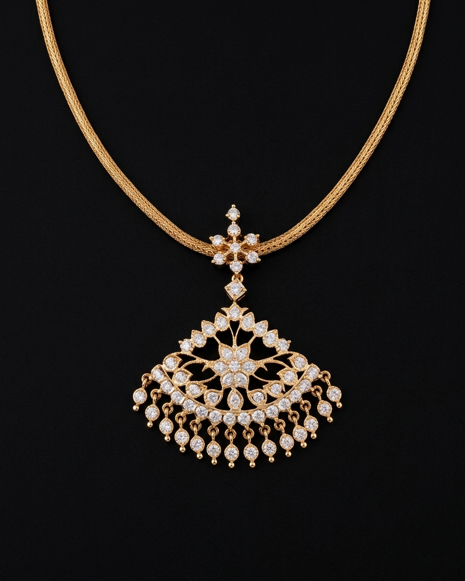 A South Indian gold necklace displayed on a dark background. The design features a smooth, thick woven gold chain supporting a star-shaped bale connected to a wide, semicircular fan pendant. The pendant is filled with intricate filigree, central flower motifs, and clear stones, finished with a cascading fringe of small round dangling stone drops.